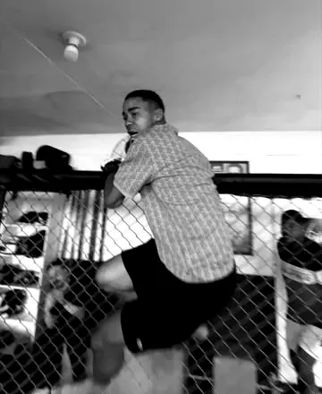 Atleta escala a grade do cage durante o treino.